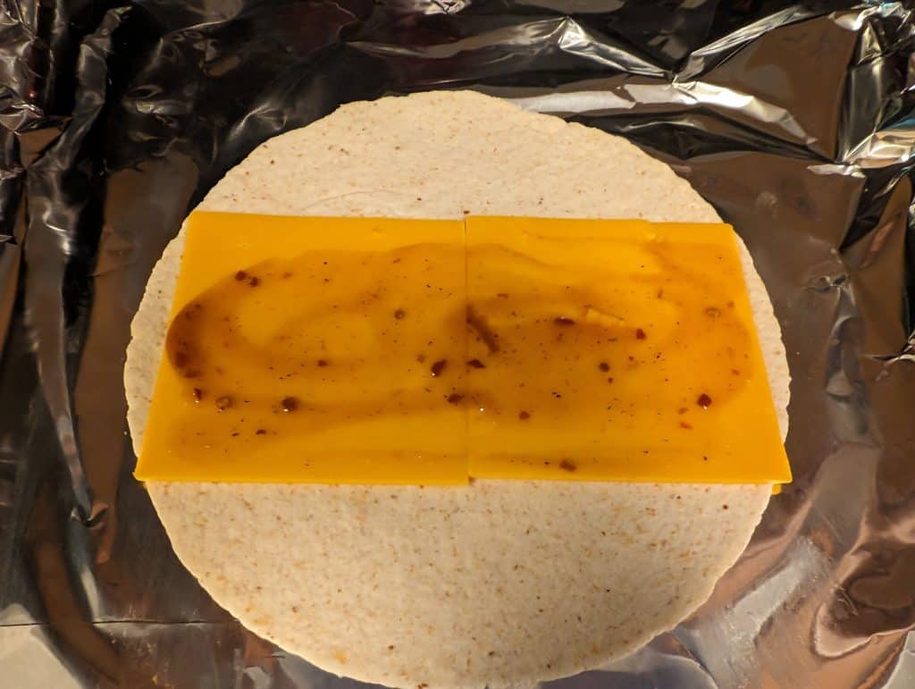 Low carb wrap with cheddar cheese and BBQ sauce spread out