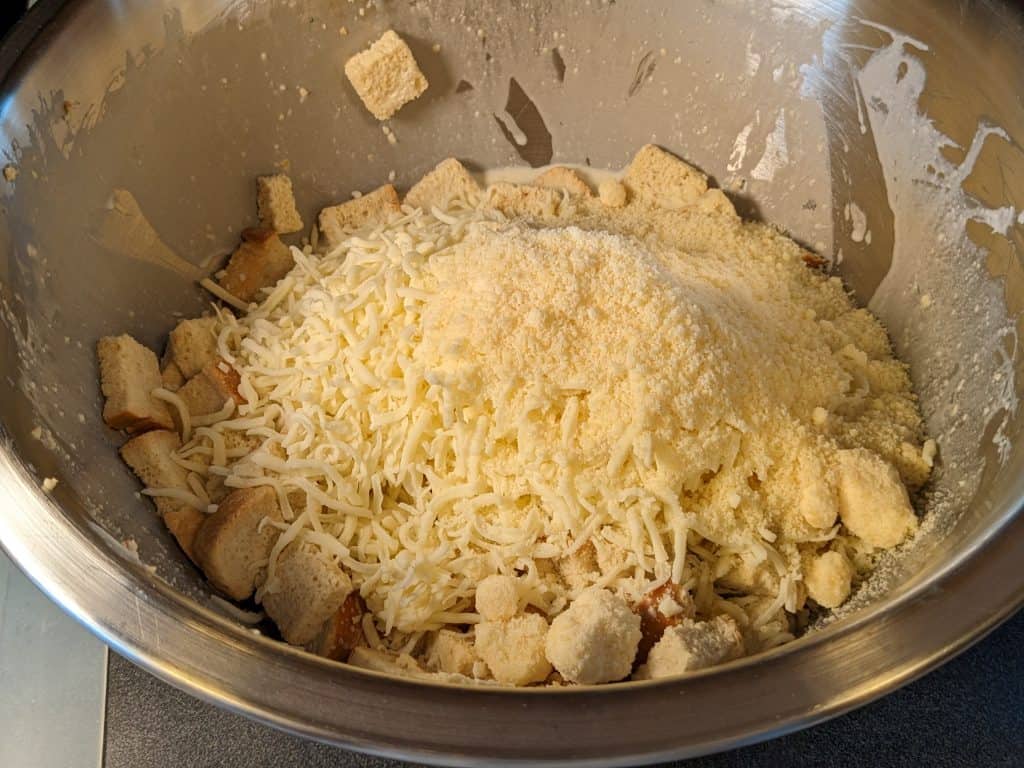 Keto Spinach and Artichoke Casserole -Bread cubes, creamy egg mixture, and cheese in bowl - not yet mixed