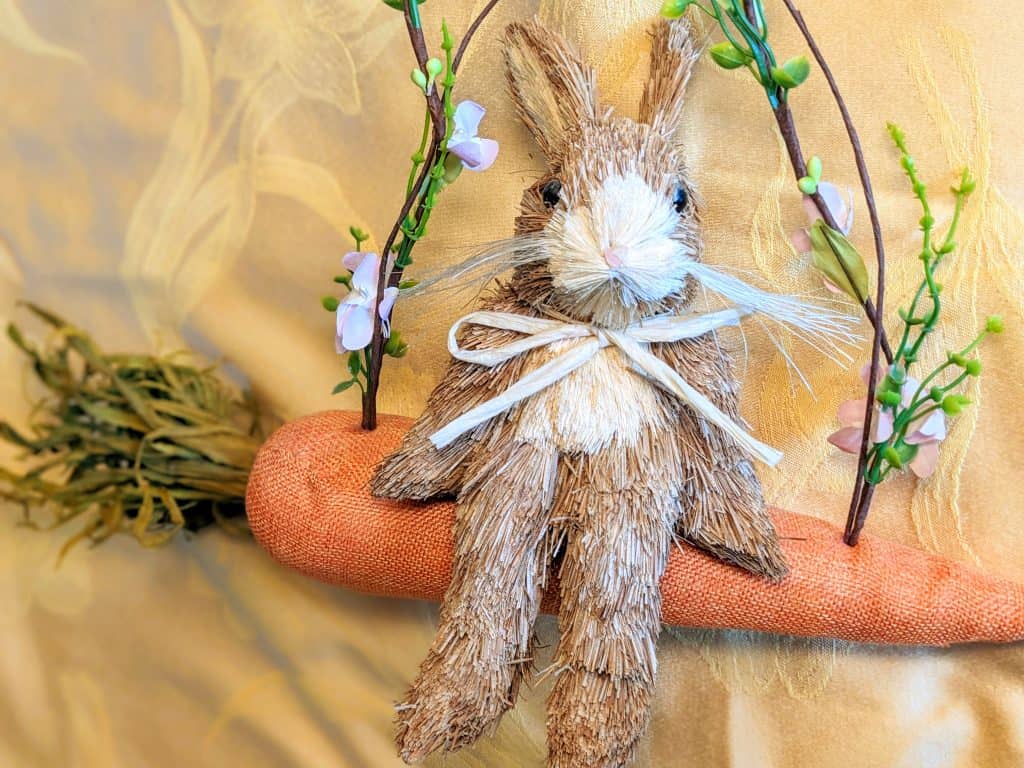 Decorative bunny sitting on a carrot that looks like swing
