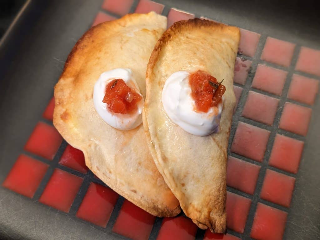 Two Turkey Empanadas finished with sour cream and salsa