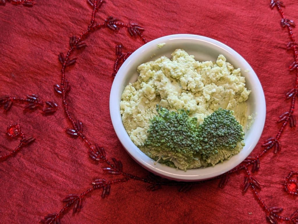 Whipped Pesto Dip with piece of broccoli in small bowl