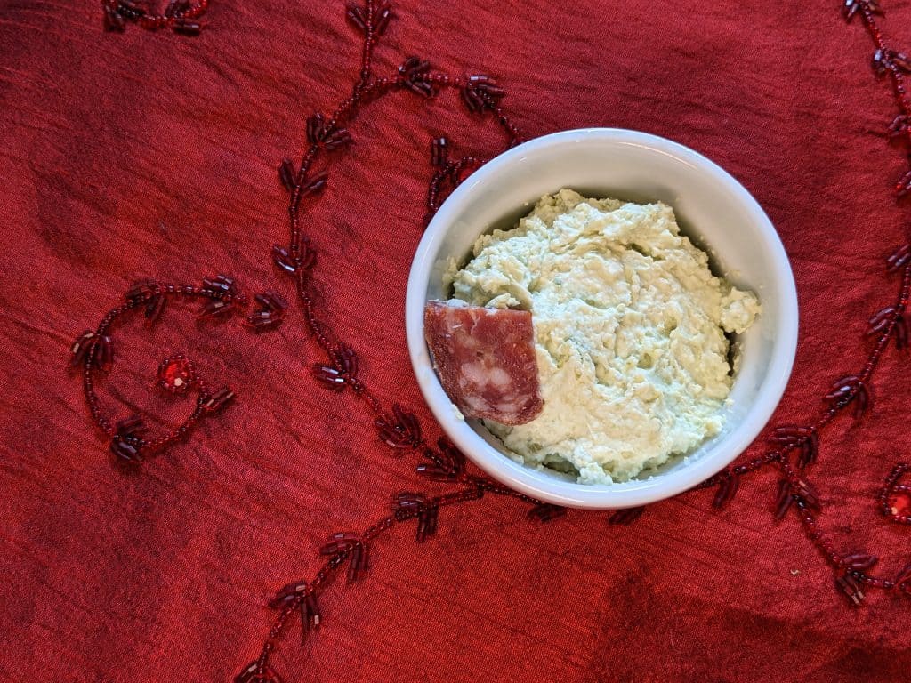 Whipped Pesto Spread with a piece of Sopressata in a small bowl