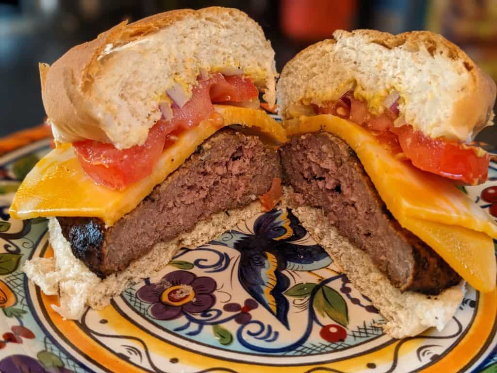 Burger with cheese, tomato, onion, and mustard on keto bun