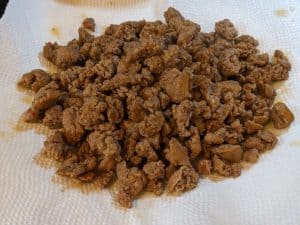Cooked crumbled sausage on paper towel lined plate
