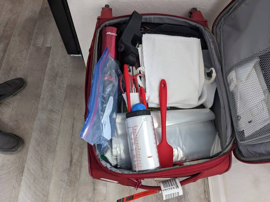 Suitcase filled with kitchen essentials for a vacation rental house