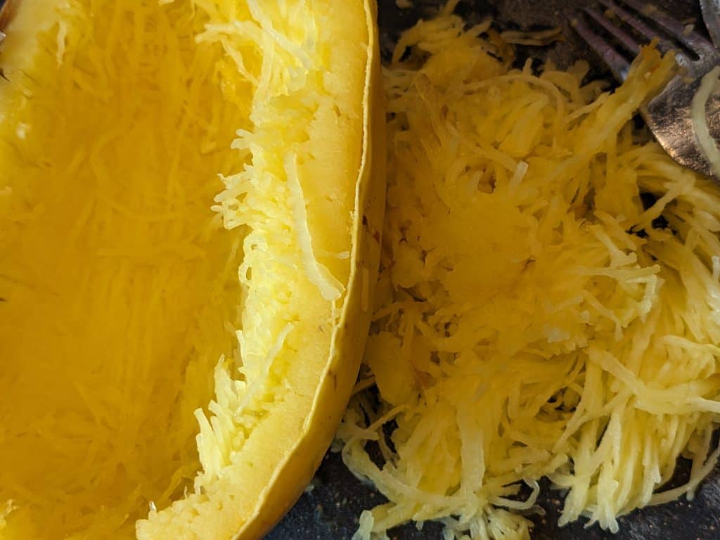 Spaghetti Squash cut in half with seeds removed and some of it shredded