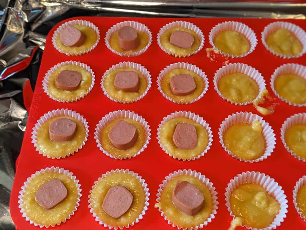 Keto Almond Flour Corn Dog Bites - Mini Muffin Pan filled with batter and half filled with hot dog pieces