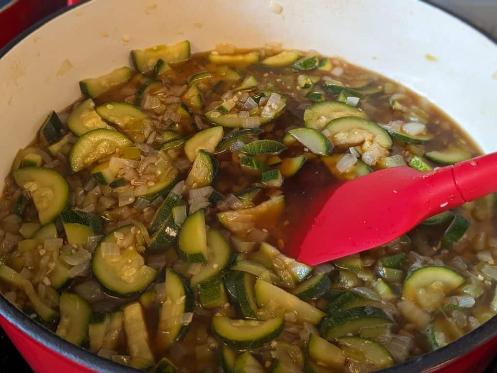Softened zucchini, onions, and cubanelle peppers in pot