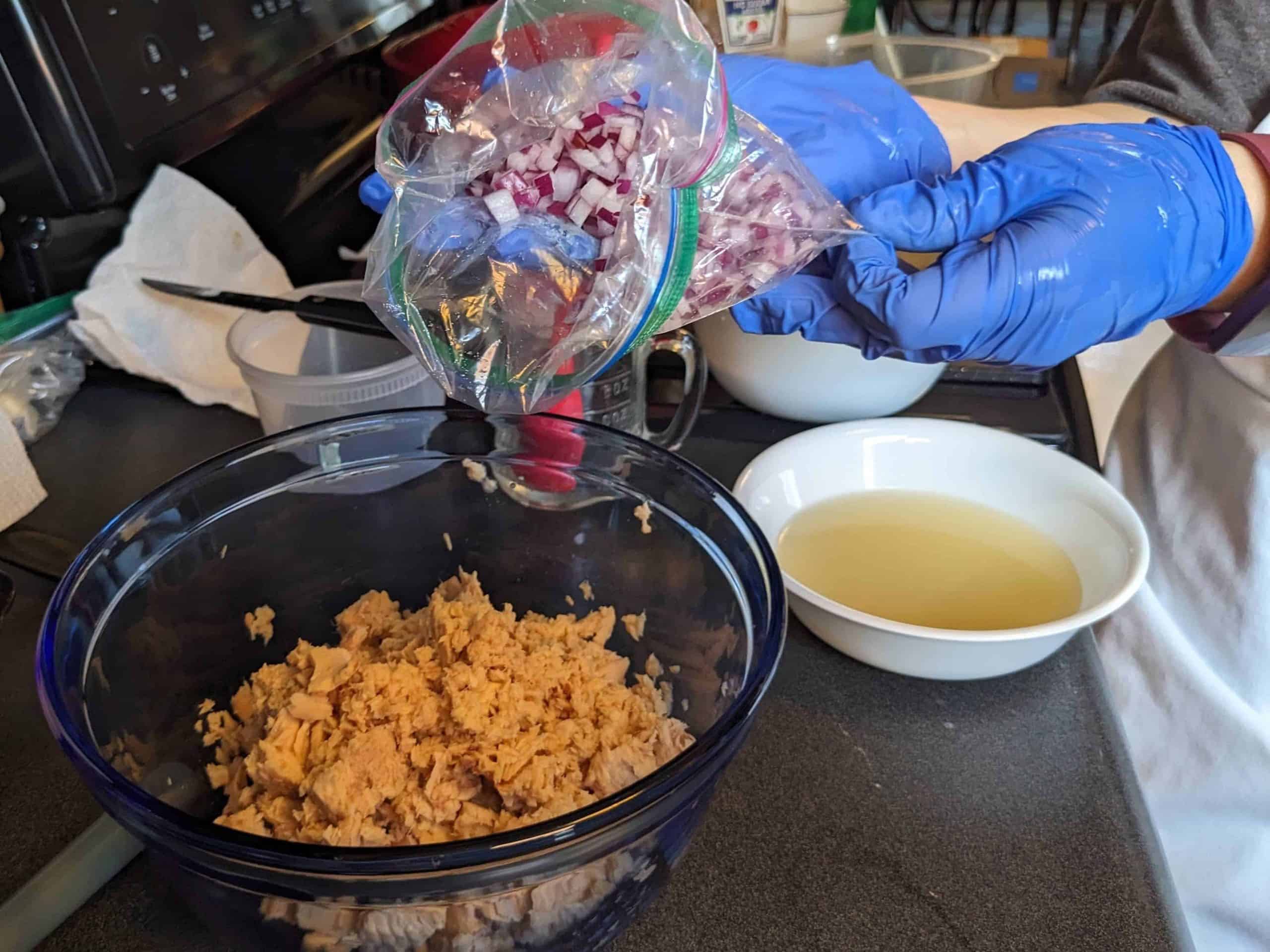 Adding diced red onion to salmon in a bowl