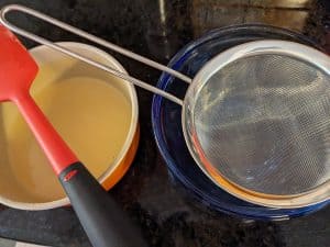 Fine mesh strainer set up to pour liquid keto vanilla pudding through