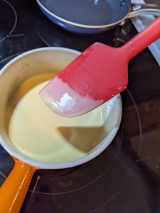 Testing the thickness of the keto vanilla pudding with a silicone spatula
