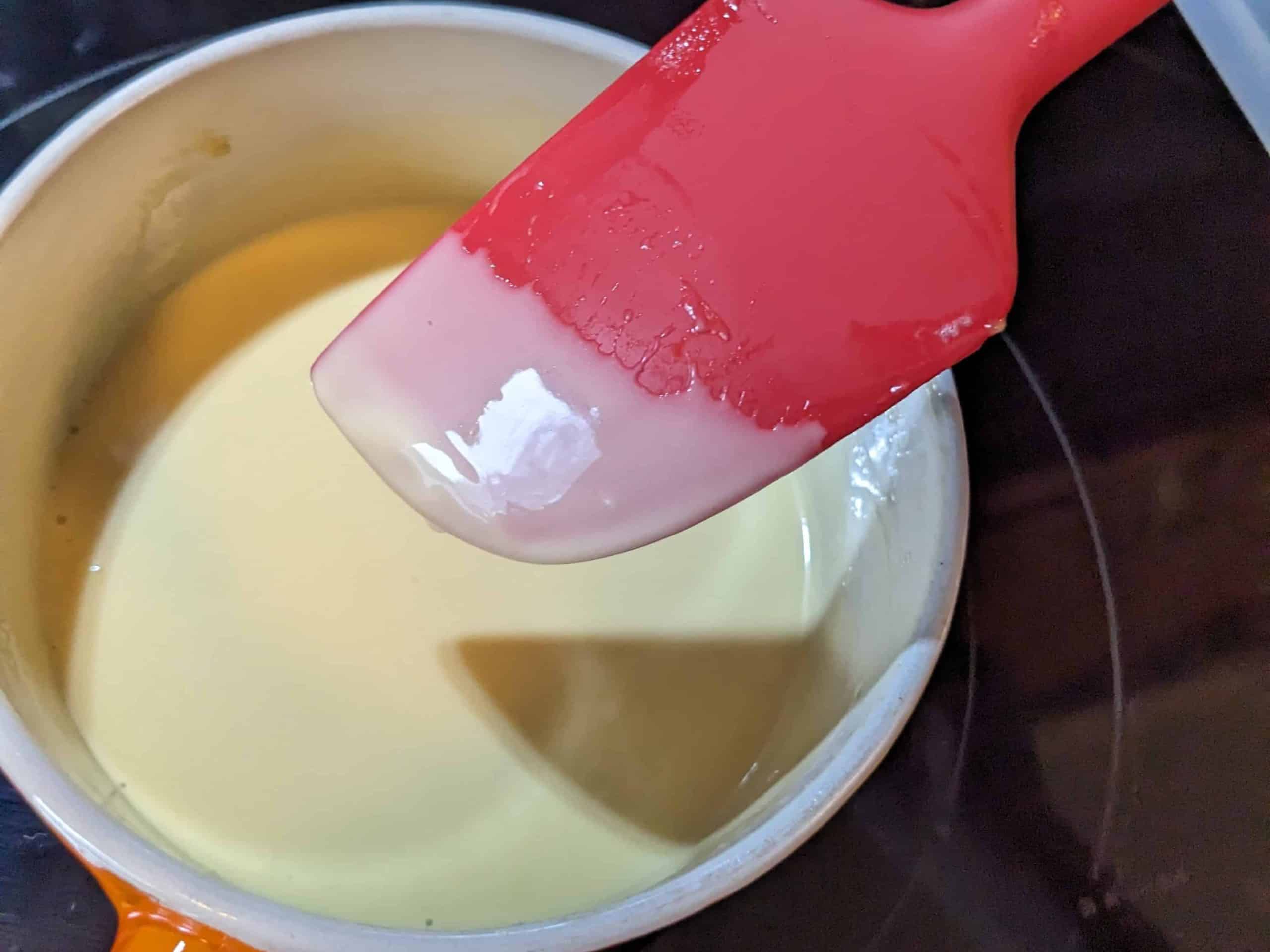 Testing the thickness of the keto vanilla pudding with a silicone spatula