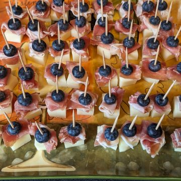 Manchego, prosciutto, and blueberry bites prepared on a serving plate