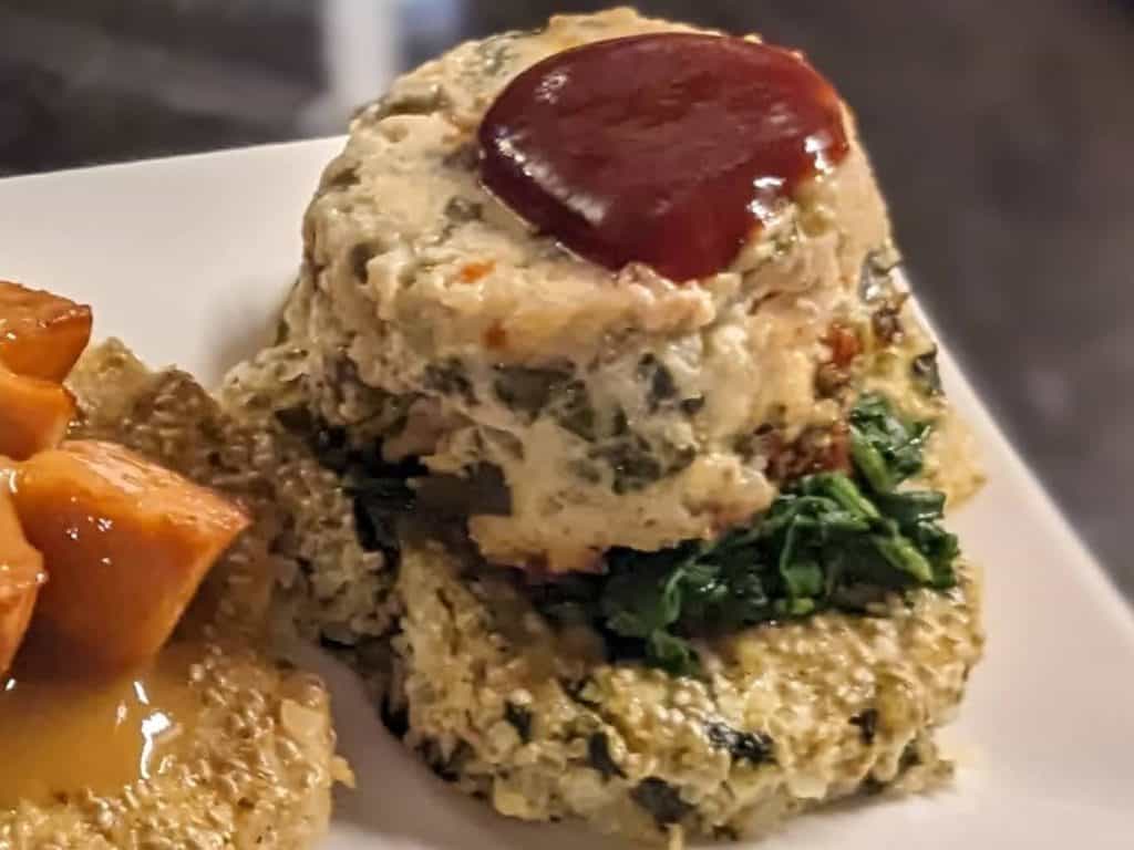 Mini Chicken Meatloaf on top of a bed of sauteed spinach and a 3 Cheese and Spinach Cauliflower Chia Cake with a drizzle of Sweet Sriracha Sauce