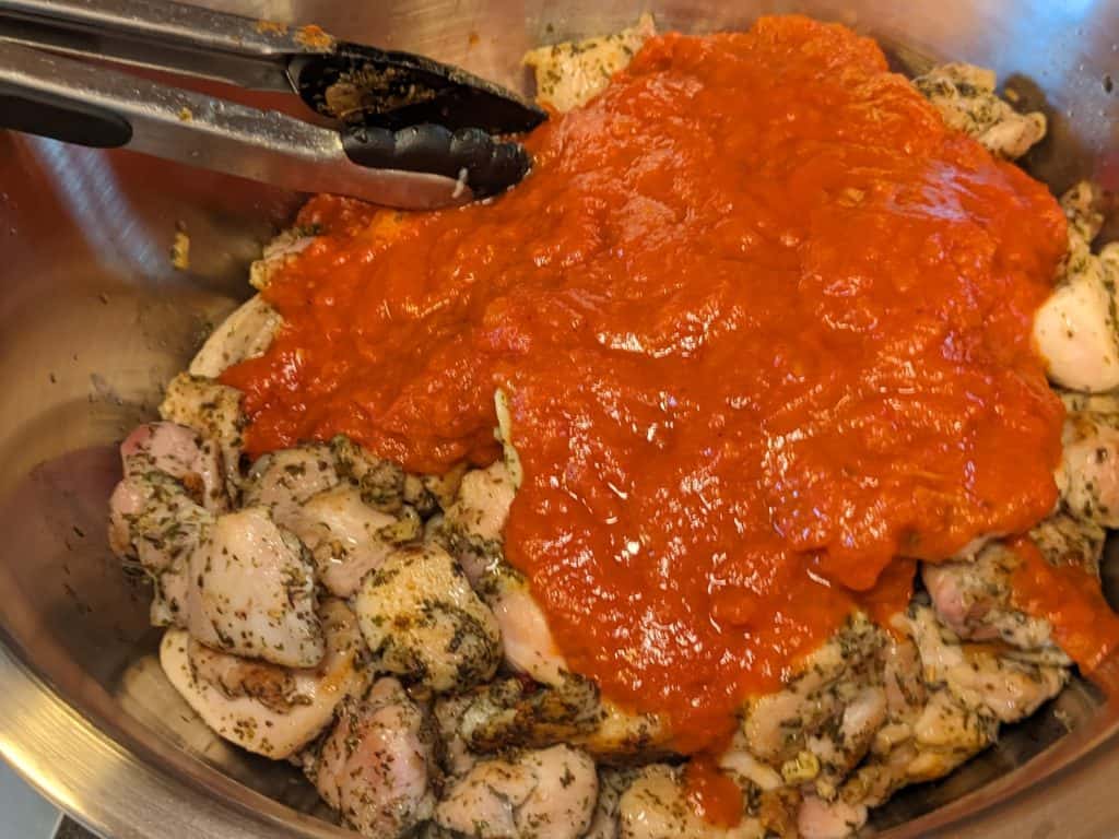 Cooked and seasoned chicken pieces in bowl with sauce