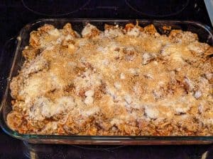 Chicken Parmesan Casserole topped with cheese and crushed pork rinds but not yet baked
