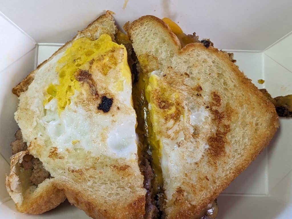 Holey Hamloaf Breakfast Sandwich - fried sandwich made with white bread slices, hamloaf, grilled onions, and a runny egg cooked in the hole of the bread