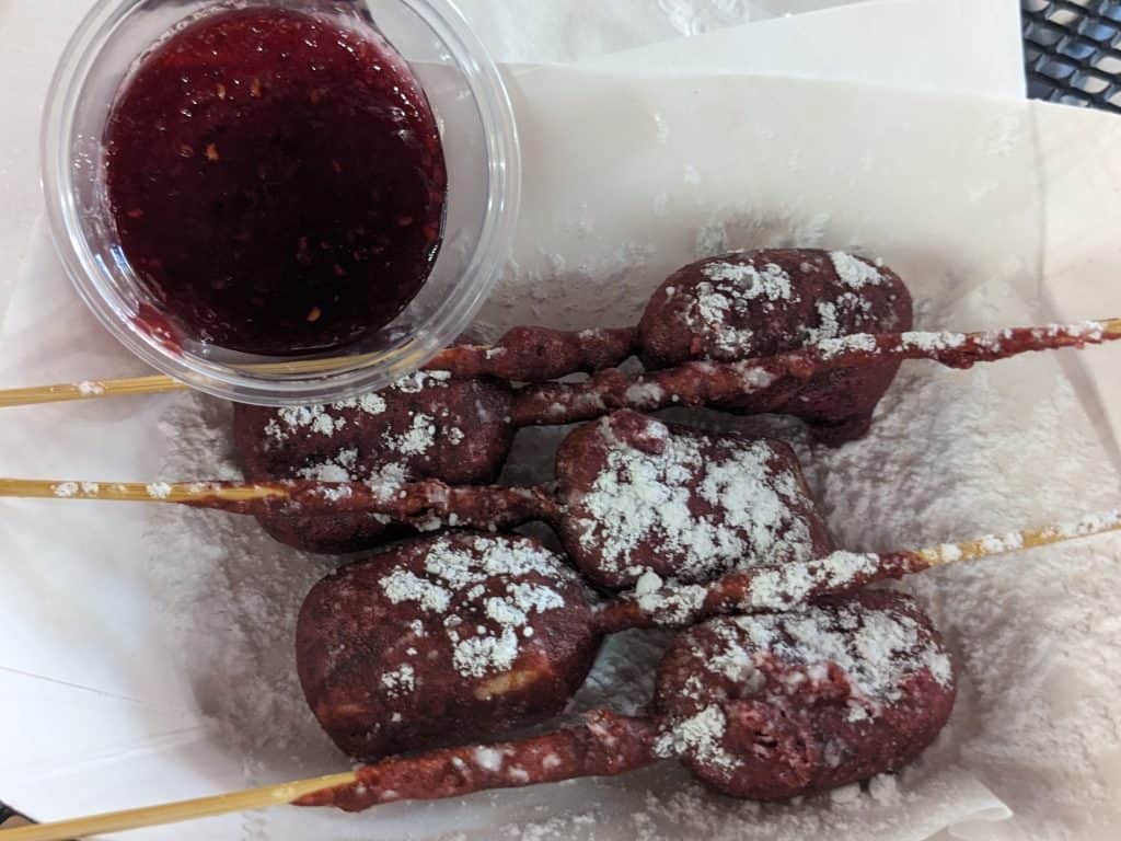 Wine Fried Brie Bites on sticks dusted with powdered sugar with a side of raspberry sauce