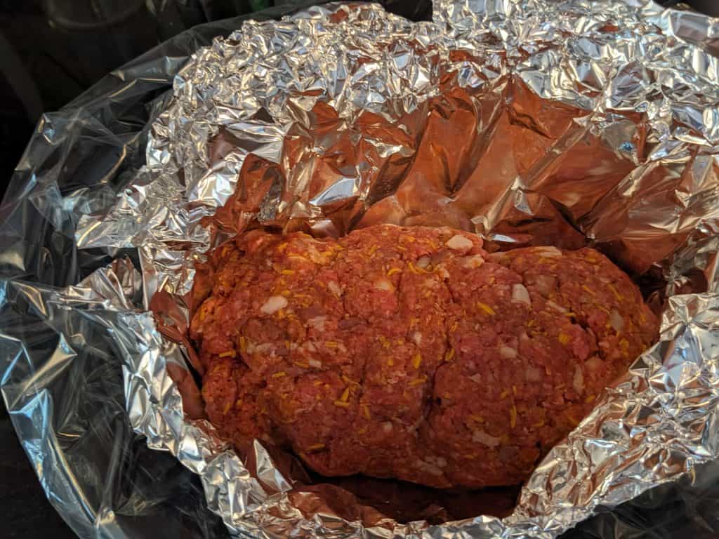 Uncooked meatloaf in foil in crockpot