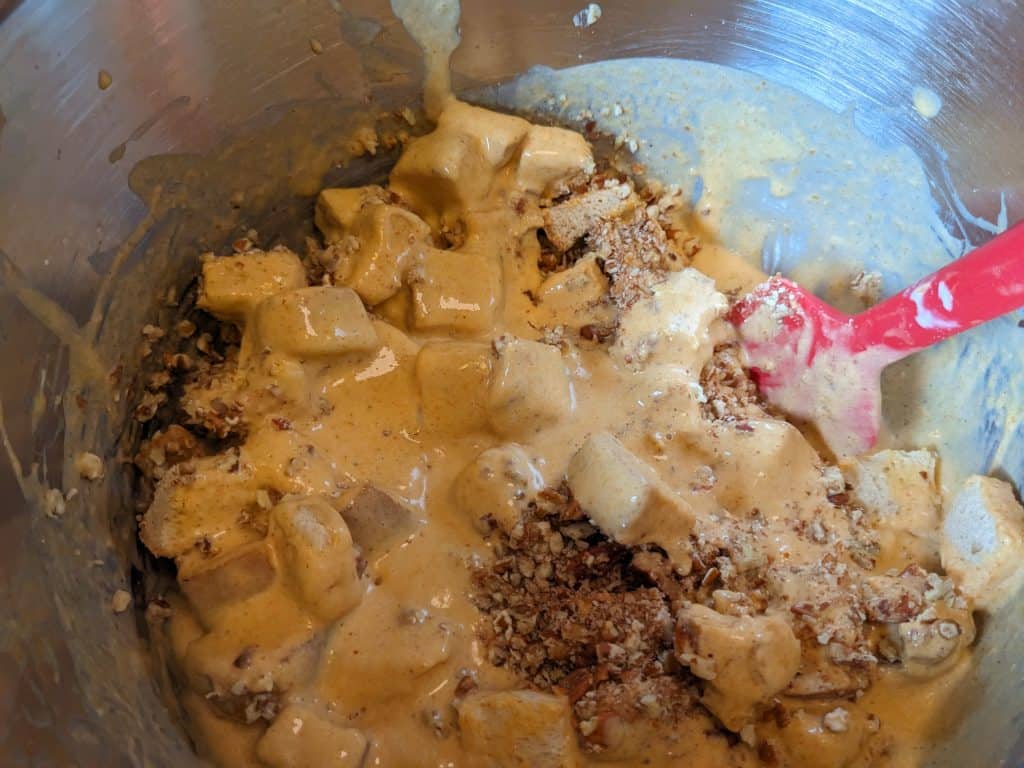 Mixing keto bread cubes, chopped pecans, and wet ingredients for Low Carb Pumpkin Bread Pudding