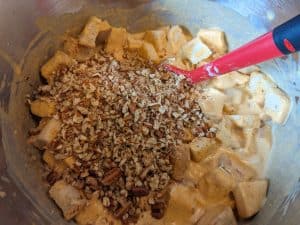 Adding chopped pecans to mixture in a bowl for Low Carb Pumpkin Bread Pudding