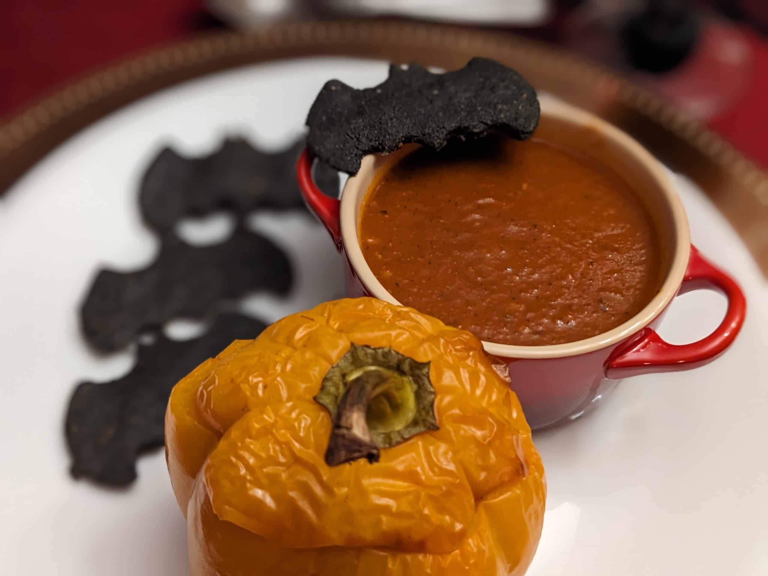 Plated bowl of Roasted Tomato Poblano Soup with Keto Black Bat Crackers and a Stuffed Pepper Jack-O-Lantern