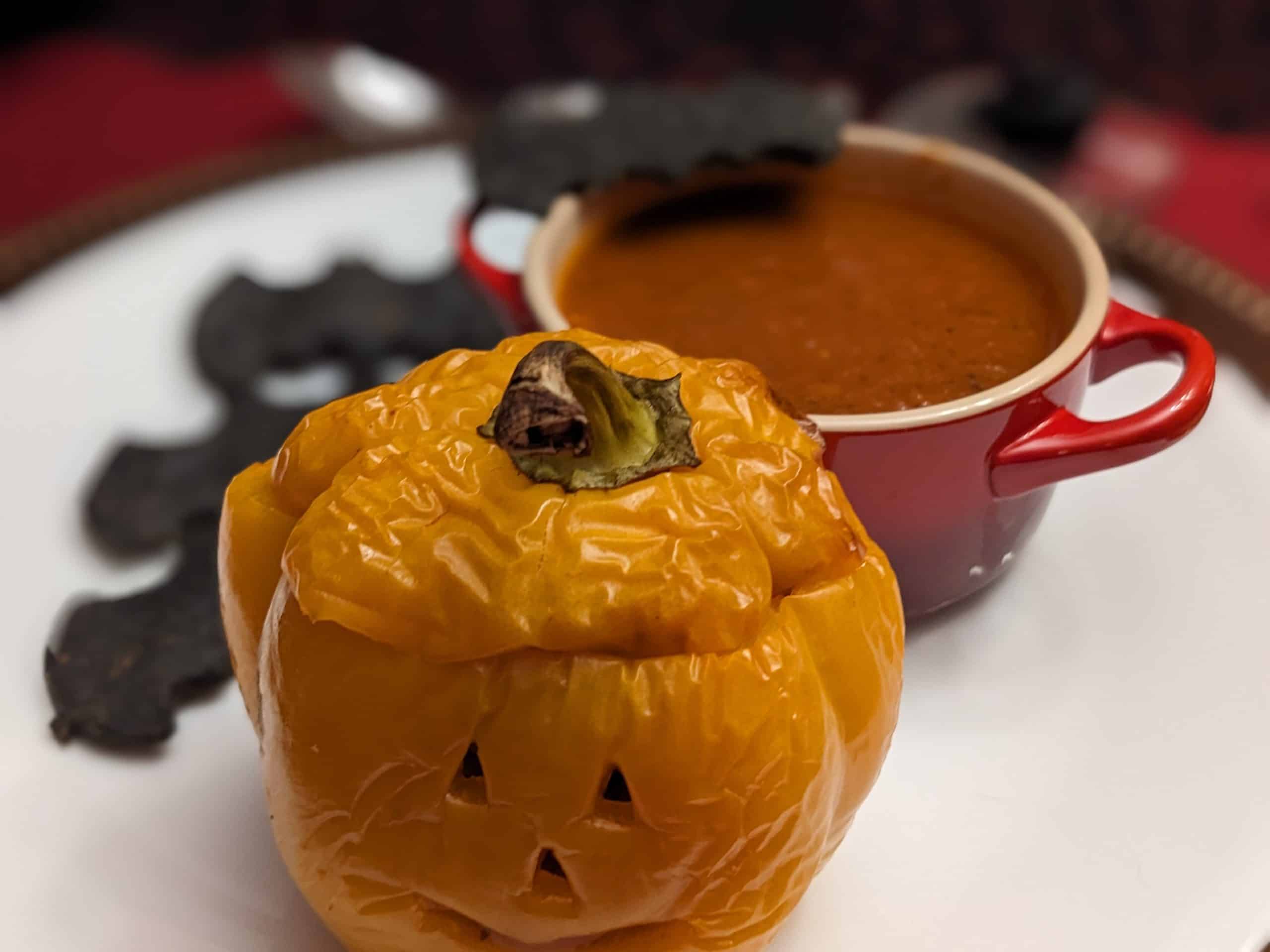 Plate with a close up of a Stuffed Pepper Jack-O-Lantern and Roasted Tomato Poblano Soup with Keto Black Bat Crackers