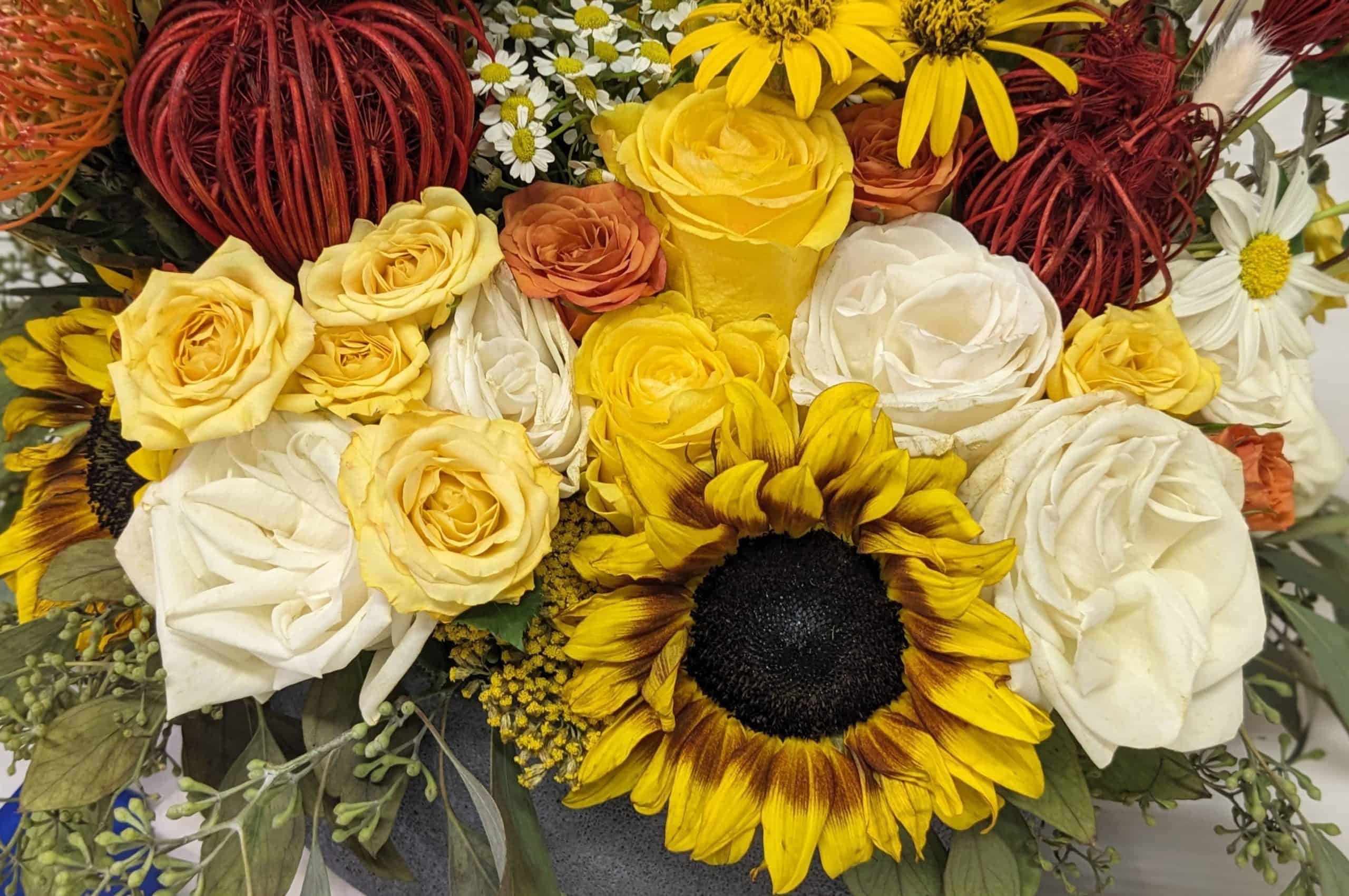 Flower arrangement with yellow, white, and orange roses and other yellow, white, and orange flowers