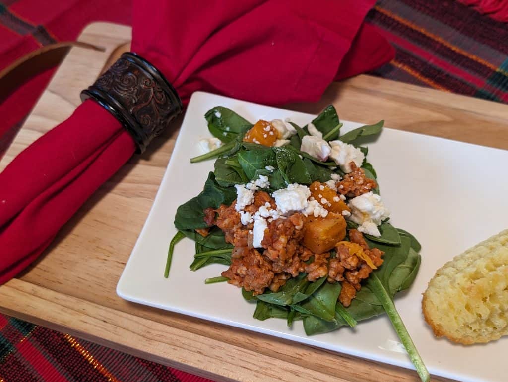 Butternut Squash Sausage Bake over Baby Spinach with Feta on a plate