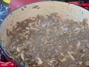 Sliced mushrooms being sautéed in a pan