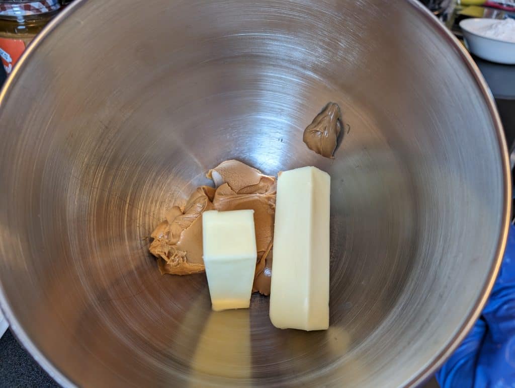 Unmixed butter and peanut butter in a mixing bowl