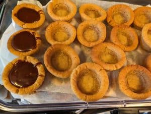 Filling Peanut Butter Cookie Cups with their Chocolate Salted Caramel Filling