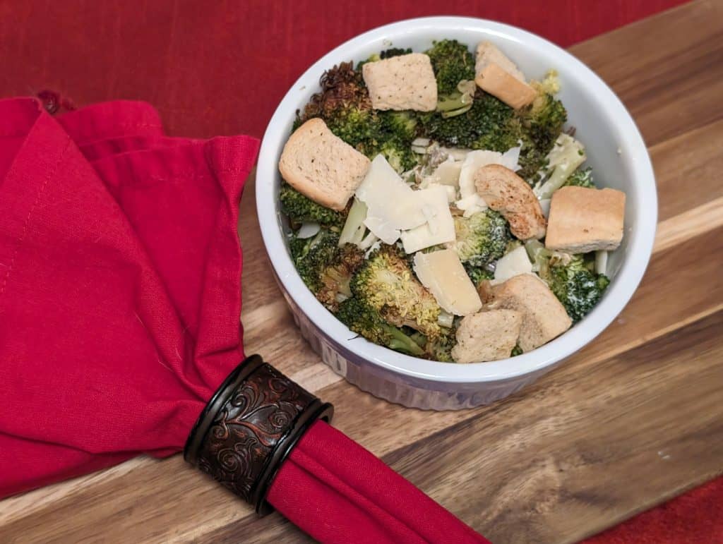 Broccoli Caesar Salad in a white ramekin dressed with keto croutons and shaved Parmesan