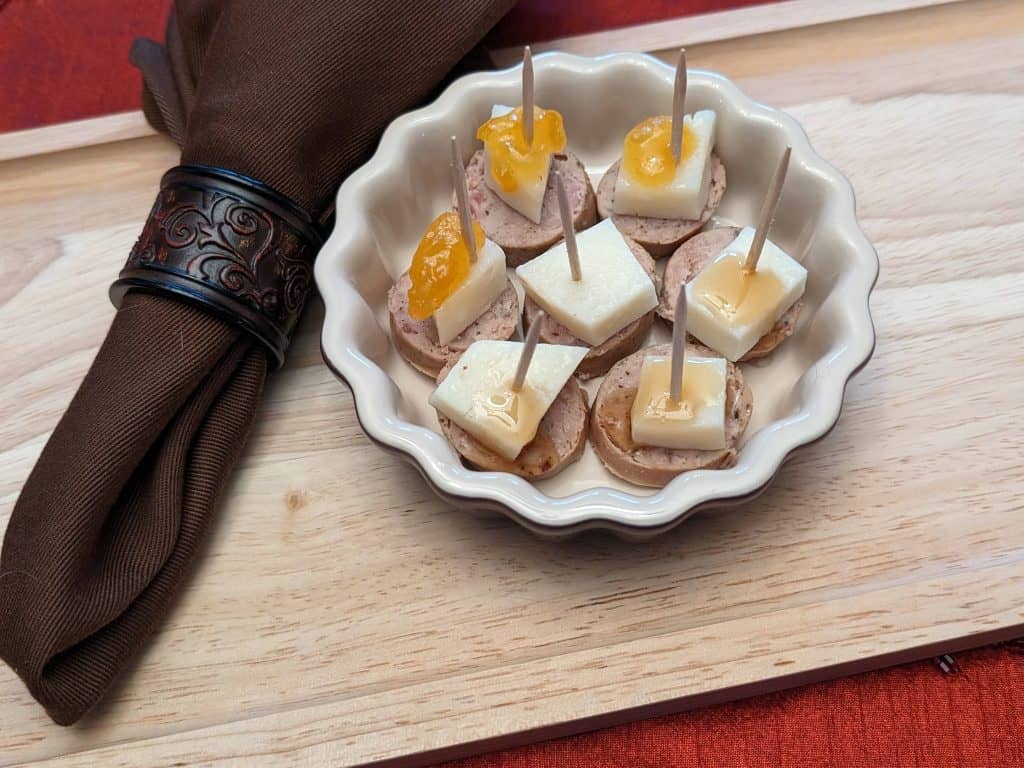 Sausage and Manchego Bites Plated showing 3 versions: no topping, topped with keto honey, topped with sugar free apricot preserves with toothpicks in them
