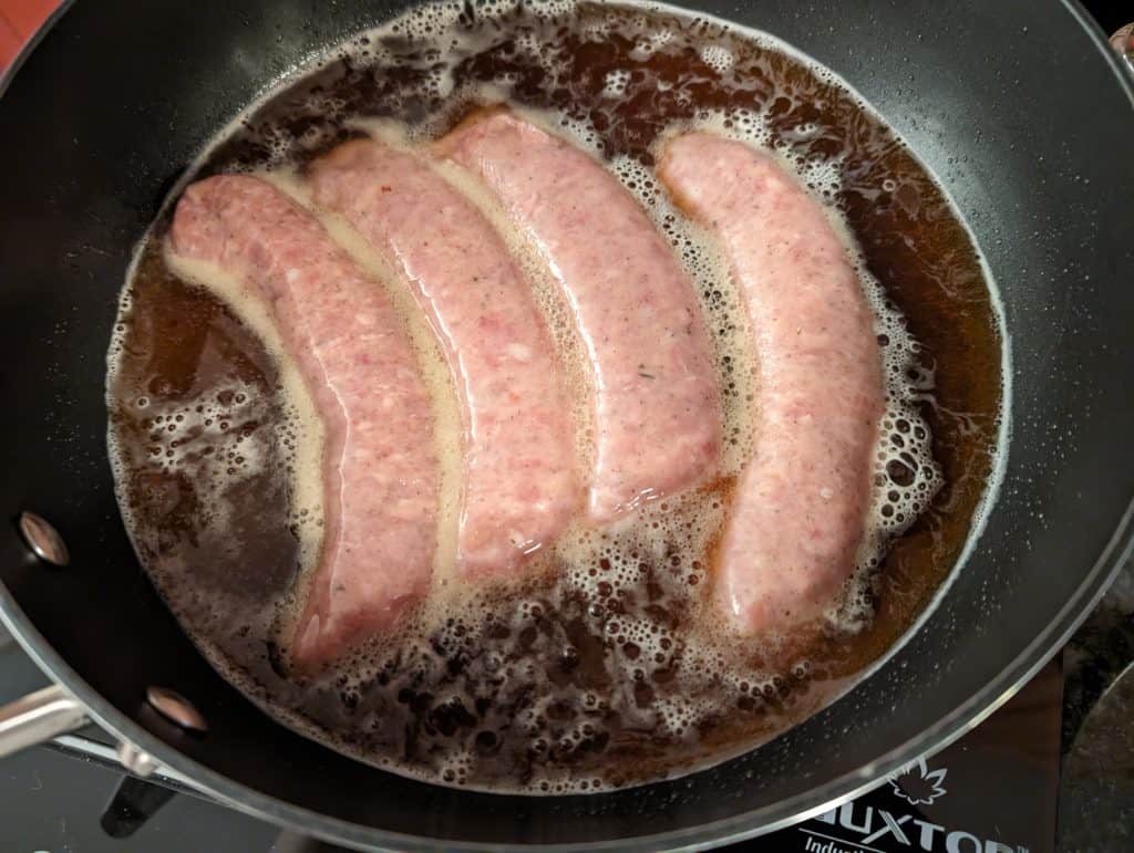 Chicken Sausages cooking in a pan with beer