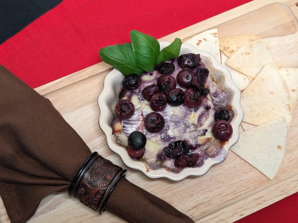 Baked Brie and Keto Pickled Blueberries in a dish garnished with some basil leaves
