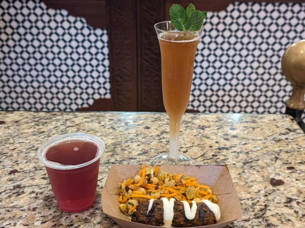 Chai Tea Mint Mimosa, Blueberry Lavender Hard Cider, and a Lamb Kebab on a table