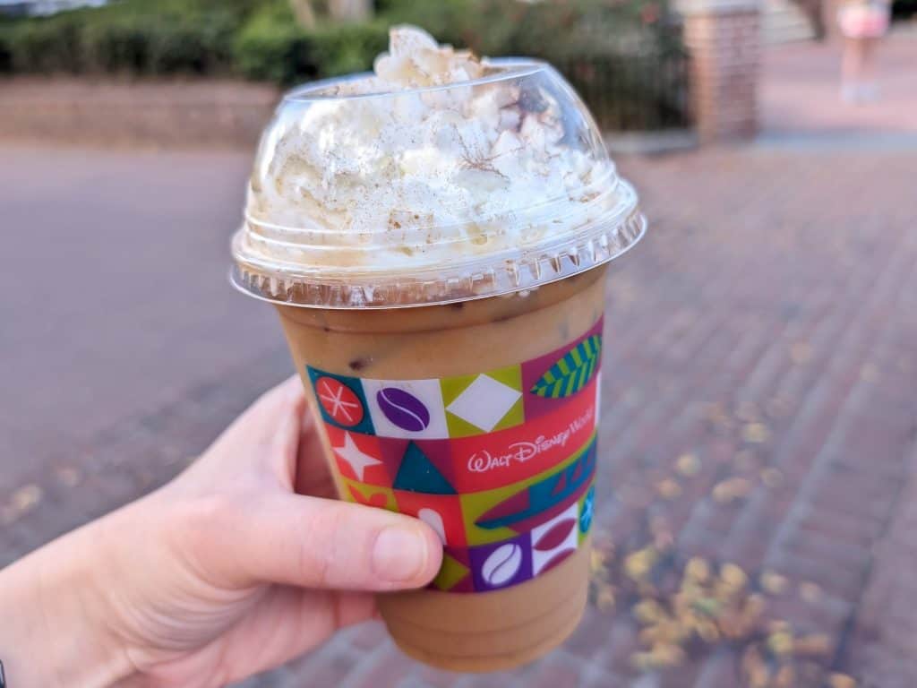 An iced Chai Tea Espresso in a plastic Walt Disney World cup with whipped cream