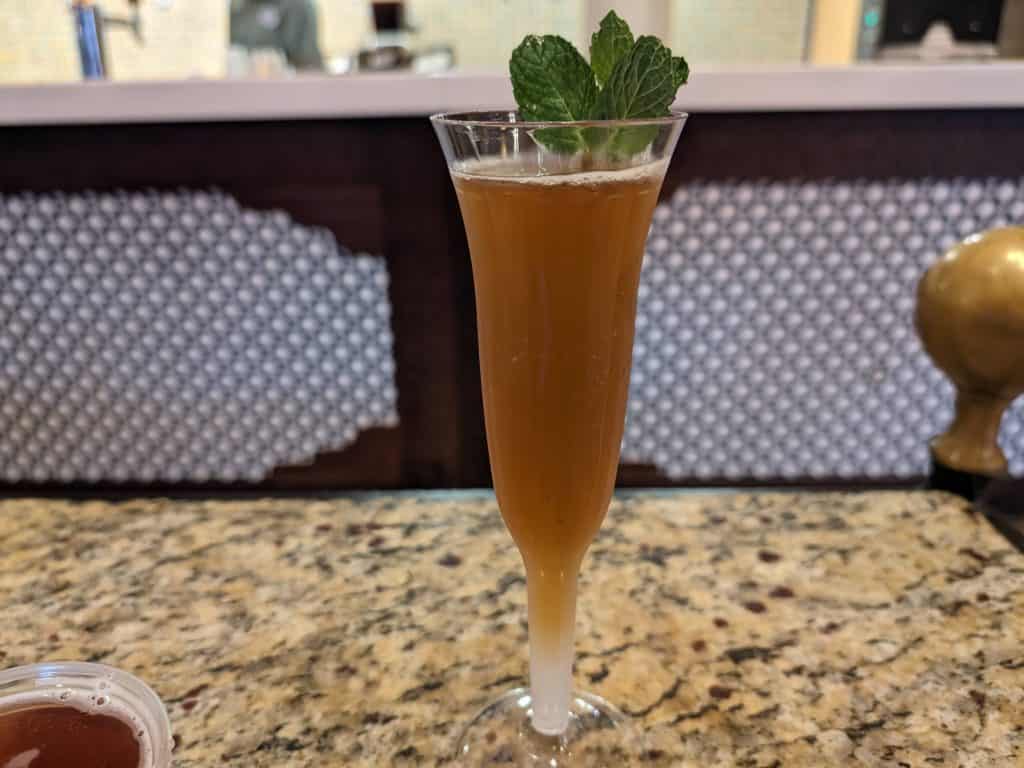 Chai Tea Mint Mimosa in a plastic champagne flute garnished with mint leaves