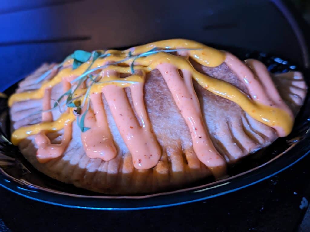 A Chorizo and Potato Empanada drizzled with two spicy mayo sauces