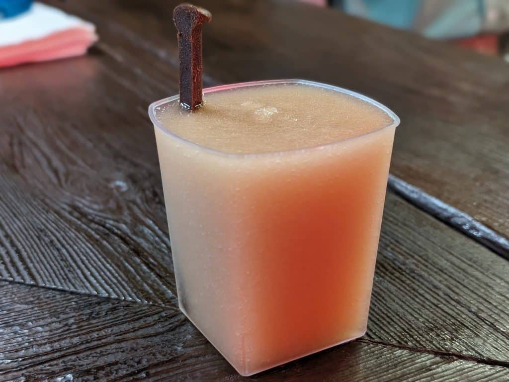 Frozen Scotch Cocktail in a plastic rocks glass with a chocolate nail sticking out of it