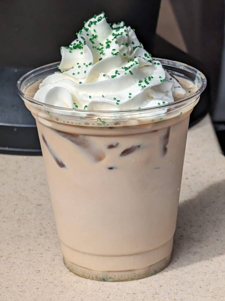 Pistachio Palette Cold Brew topped with whipped cream and green sprinkles in a plastic cup