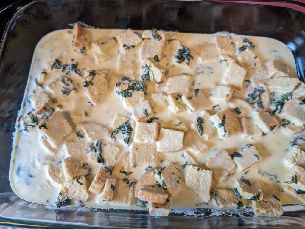 First layer in pan of egg, cream, bread, and spinach mixture for Keto Florentine Breakfast Strata