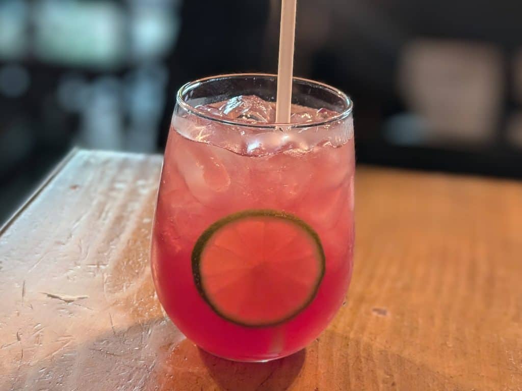 Pink cocktail with a slice of lime in a low-ball glass