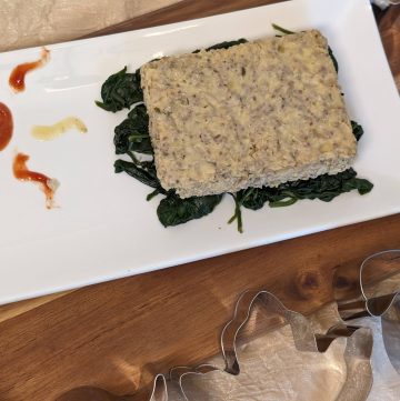 Ranch Cauliflower Chia Cakes plated on a bed of sautéed spinach