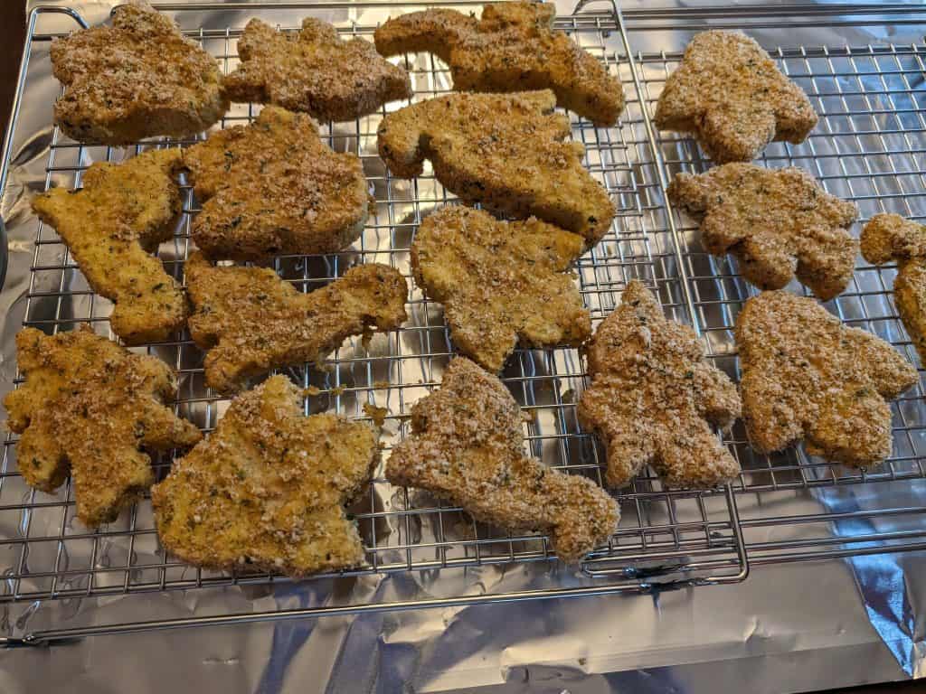 Breaded and baked Gluten-Free Dinosaur Chicken Patties (Keto) on a wire rack insert on a baking sheet