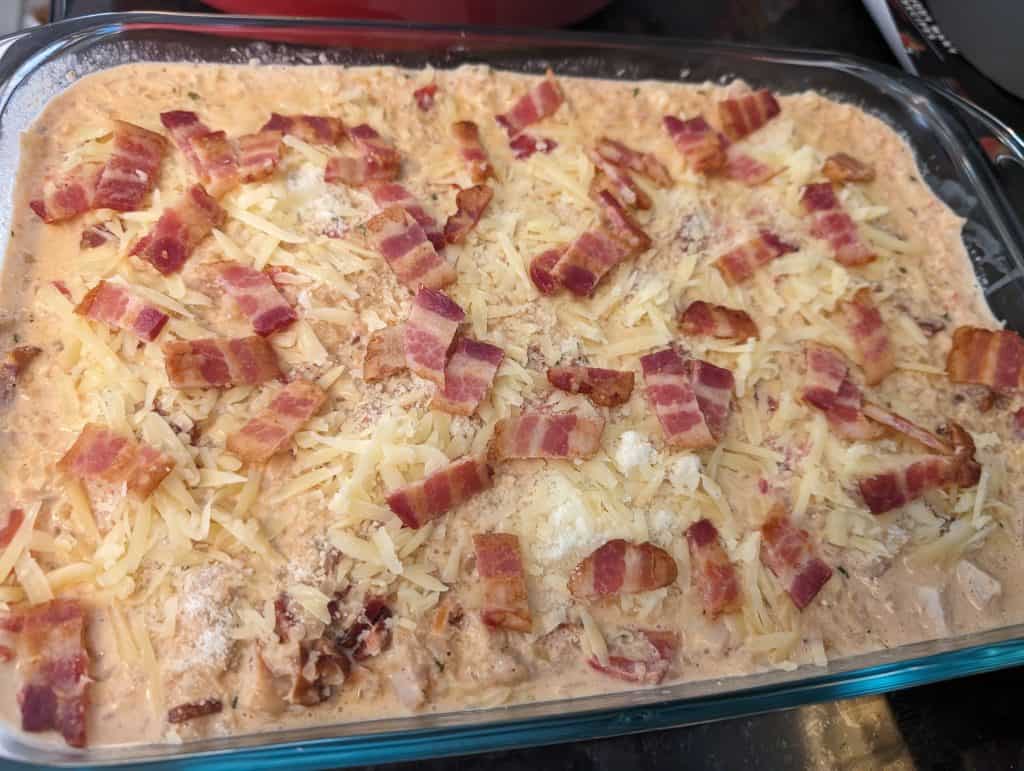 Creamy Keto Turkey Bacon and Tomato Casserole ready to bake in a casserole dish topped with cheese and bacon