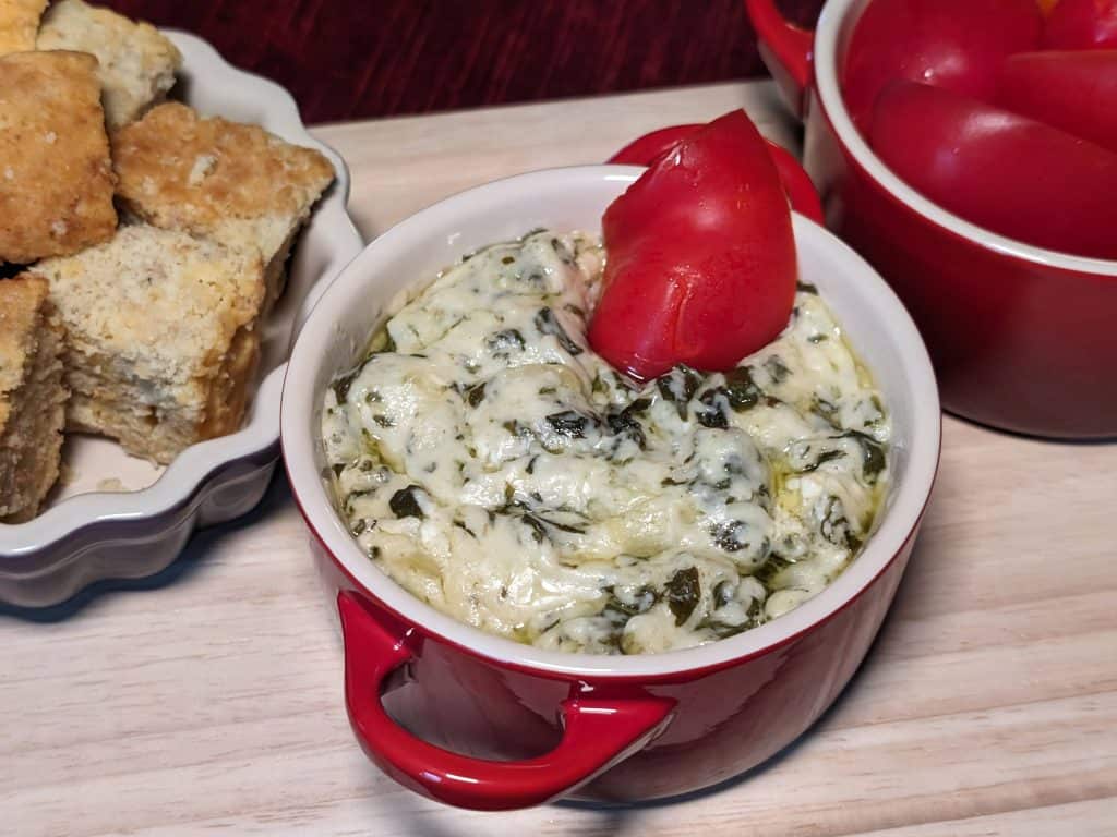 Spinach and Artichoke Dip in a small coquette with sliced red bell peppers for dippers