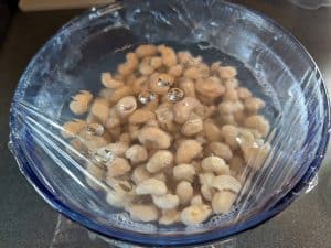 Soaking cashews in a bowl covered with plastic wrap