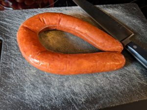 Frozen smoked sausage on a cutting board with knife